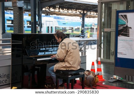 PARIS, FRANCE - DECEMBER 15, 2013: Man playing piano at Gare de l'Est (Paris Est train station). Several pianos are found at Parisian train stations allowing the passengers to play for their pleasure.