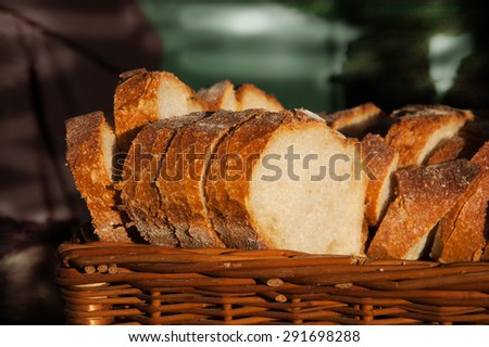 Fresh sliced bread in a wicker basket in dark interior. A game of light and shadow.