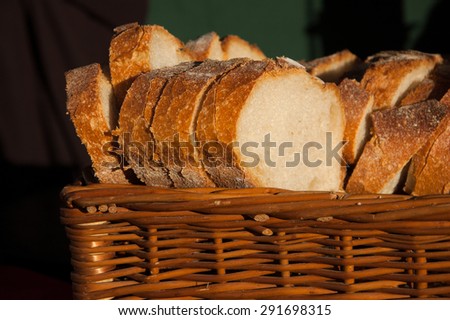 Fresh sliced bread in a wicker basket in dark interior. A game of light and shadow.