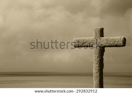 Stone Cross above the sea. Mers-les-Bains (Picardy, France) Aged photo. Sepia. Sunlight glowing through the clouds (left corner).