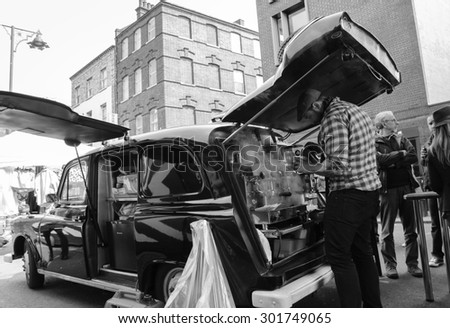 LONDON, ENGLAND, UK - MAY 4, 2014: Unidentified barista making coffee in mobile cafe (former old cab car) at Brick Lane market area.