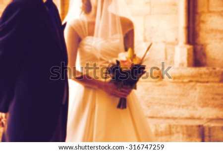 Blurred photo of bride and her father waiting before entering to the church on wedding day (father is taking his young daughter to the altar). Toned image.