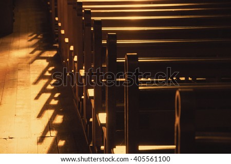 Rows of church benches. Sunlight filtered through the stained glass window. Selective focus. Sepia photo.