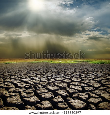 dramatic sky with sun over drought earth