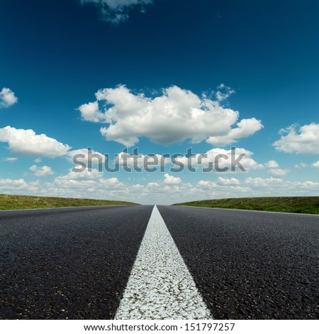 asphalt road to horizon in deep blue cloudy sky