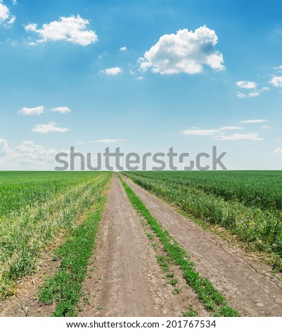 empty countryside road with green grass and clouds
