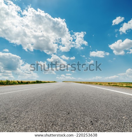 asphalt road to horizon and clouds over it