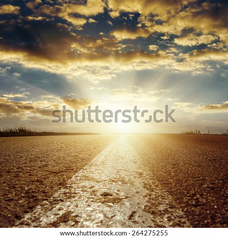 sunset in low clouds over asphalt road with central white line