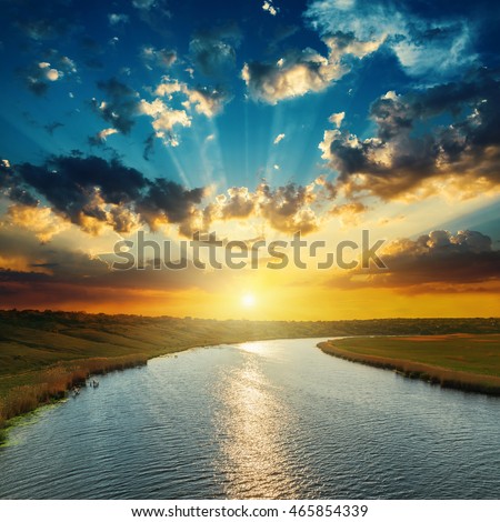sunset with clouds, light rays over river with reflections