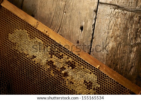 yellow honeycomb on frame with fresh honey on wooden table.