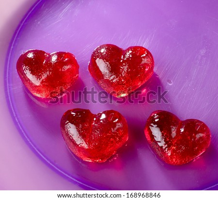 Valentines day, red sweet candies in heart shape, into a purple plate