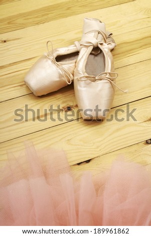 pair of ballet shoes pointes with ribbons on wooden floor