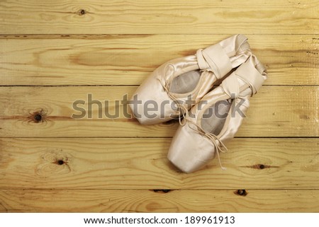 pair of ballet shoes pointes with ribbons on wooden floor