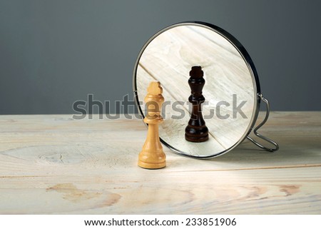 Black or white king chessmen in front of the mirror, concept about racism.
