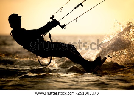 High resolution and superb quality photo of a rider doing kitesurfing tricks, with backlit sunset
