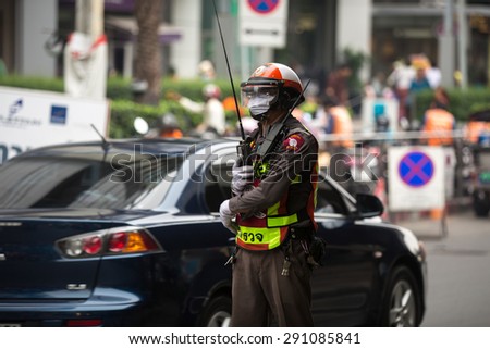BANGKOK, THAILAND - MARCH 2, 2015 : Unidentified traffic police officer works on a busy road. Police regularly direct traffic in busy areas.