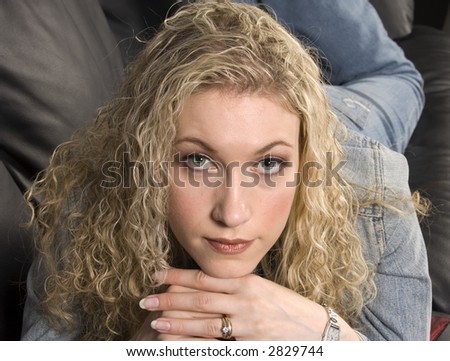 Blond girl laying on couch resting chin on hands