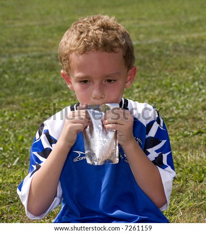Young boy drinking from a pouch at soccer game halftime