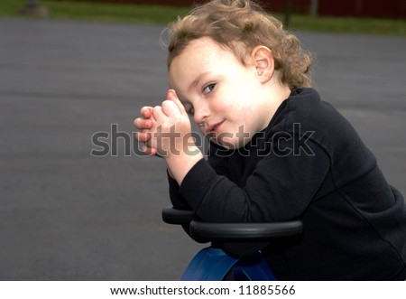 Young boy giving sideways sly glance while sitting outside