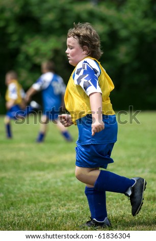 Young boy soccer player running on filed very red faced and sweaty