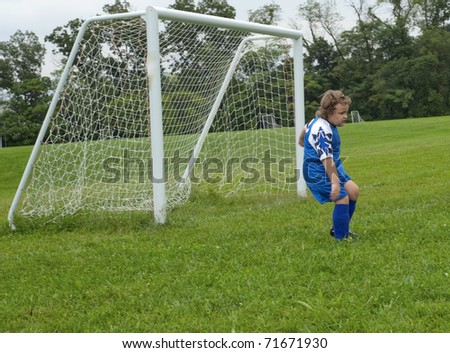 Young soccer goalie during game with net behind on green grass