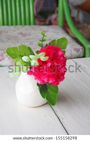 artificial flowers in white vase on wood desk