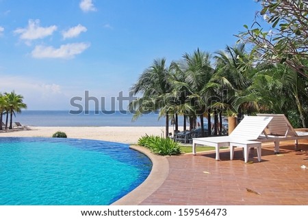 White beach chair and swimming pool near sea on sunny day ,Thailand