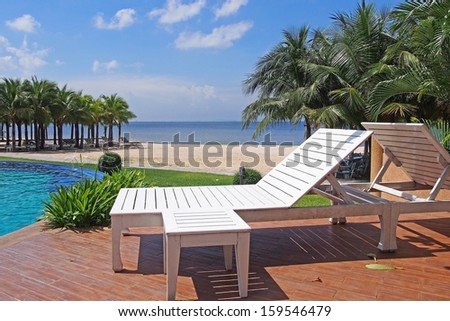 White beach chair beside swimming pool near sea on sunny day ,Thailand