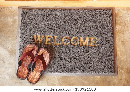 welcome mat with brown sandals on floor