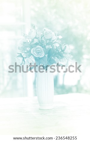 artificial roses in ceramic vase near window with morning light, in soft blue color