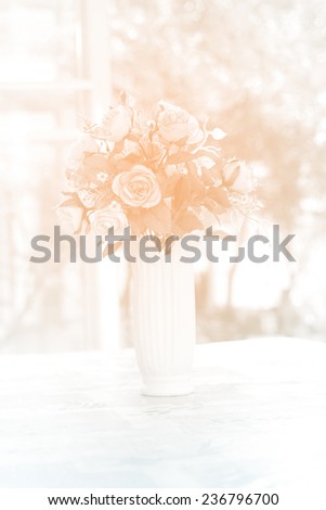 artificial roses in ceramic vase near window with morning light, in soft orange color
