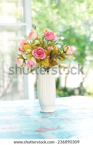artificial roses in ceramic vase near window with morning light, in soft blue color