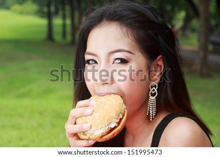 Teenage Girl Eating a Cheeseburger in the park