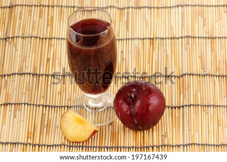 Fresh plums and a glass full of plums juice