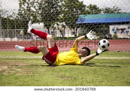 Goalkeeper catches the ball in the football field