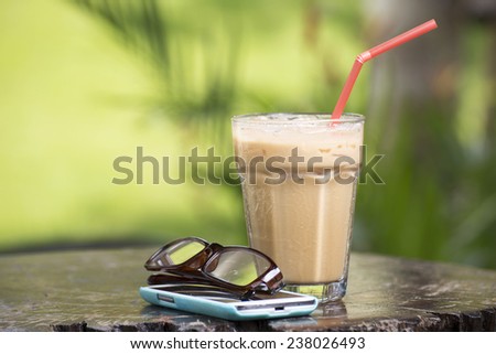 Thai ice coffee on the table with mobile phone and glasses