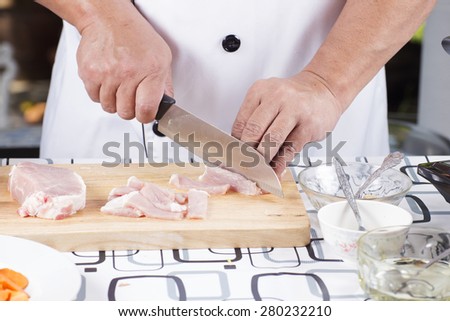 Close up of Hand\'s Chef cutting raw pork on wooden board / Cooking Japanese pork curry concept