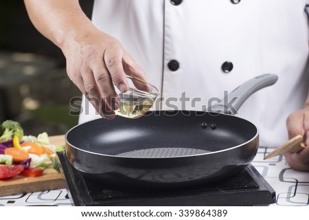 Chef pouring vegetable oil to the pan / Stir fried vegetable concept