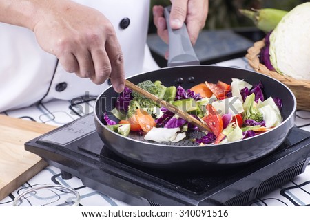 Chef cooking stir fried vegetable on the pan