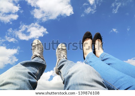 legs dangling in the blue sky with clouds