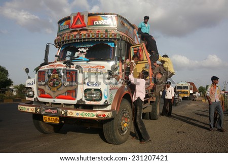 GUJARAT, INDIA - CIRCA MAY 2012: Hitch hikers disembark from Indian truck on busy highway