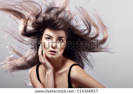 fashion woman with flying hair on a gray background.