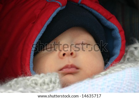 Little baby sleeping outside in his stroller on a winter day