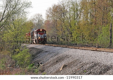 A train coming towards you from the left out of some trees