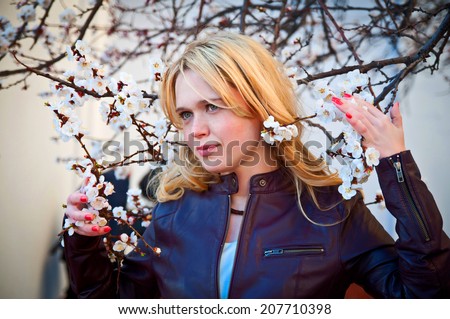 young woman with fringe and red hair near apricot flowering tree