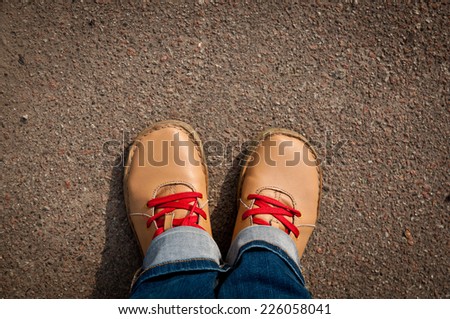 nice camel color shoes with red shoelaces and blue jeans at the asphalt