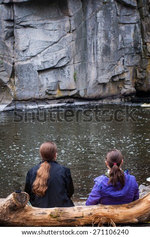 couple of hikers enjoy river under rock mountain on the tree trunk