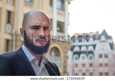 bearded successful man in suit in city