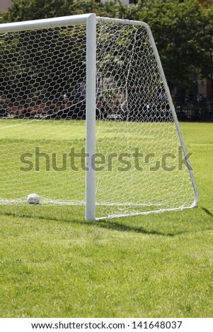 A shot of a soccer goal at the end of a empty field at a park