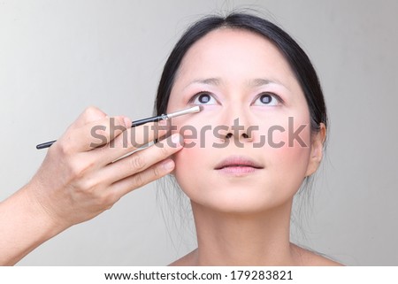 Beautiful  asian woman doing make-up on face with cosmetic brush.